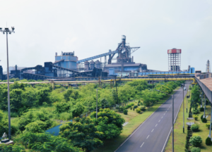 A steel plant in the background with an area planted with trees in front of it. The location is India.